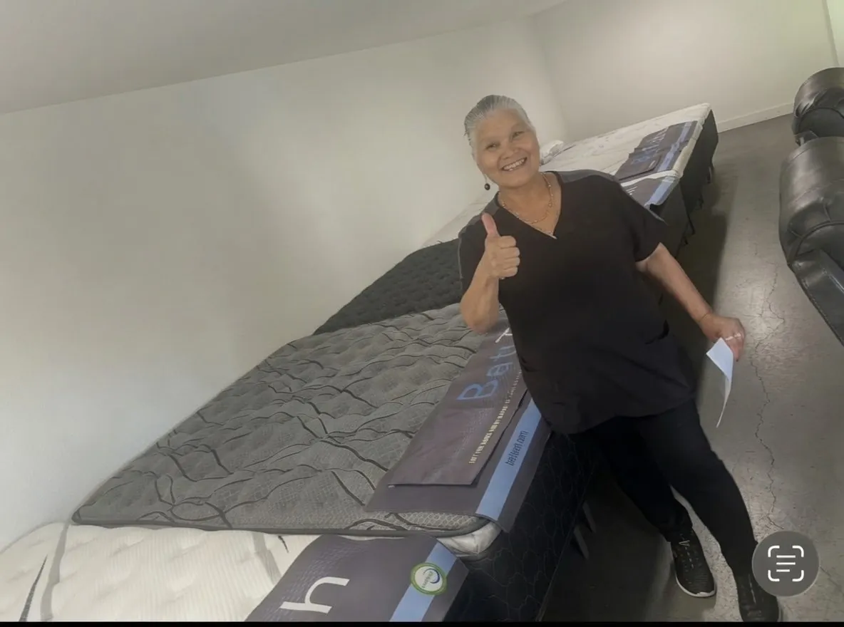 Rows of brand new mattresses at the mattress warehouse in Elk Grove with a happy customer giving a thumbs up