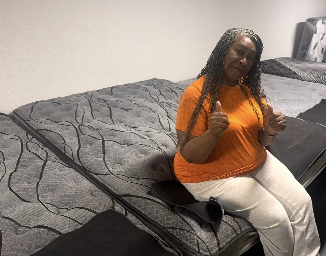 Customer giving a thumbs up by mattresses at our Elk Grove showroom